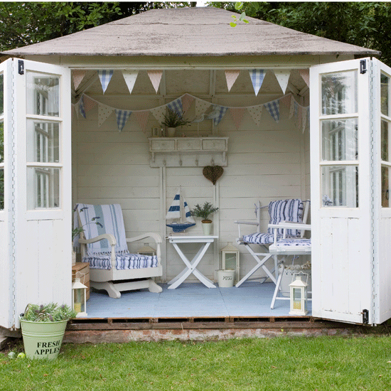 White painted garden room with blue and white chairs, table and bunting
