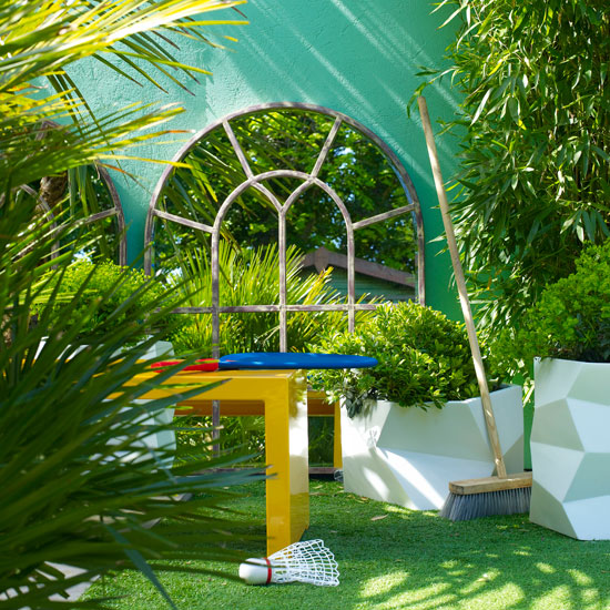 Small garden with wall mirror and yellow plastic table