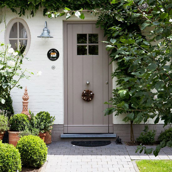 Small country-style front garden with planters, grey front door and trellis