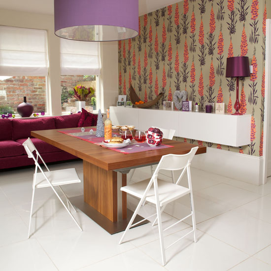 Contemporary dining room with printed wallpaper, white folding chairs and wooden table