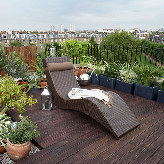 Small roof garden with wooden decking, potted plants and sun lounger