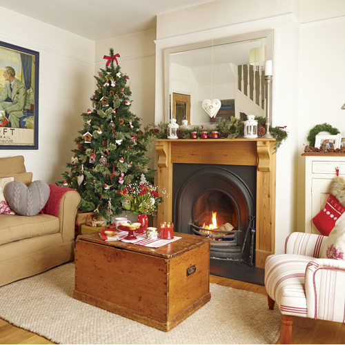 Country Christmas living room with neutral walls, wood flooring, neutral rug, white and red striped upholstered chair and Christmas tree 
