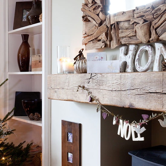 Country Christmas living room with wooden beam mantelpiece, wooden mirror frame and Christmas decorations