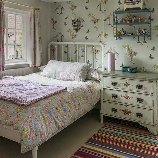 Girl's bedroom with motif wallpaper and iron bedstead